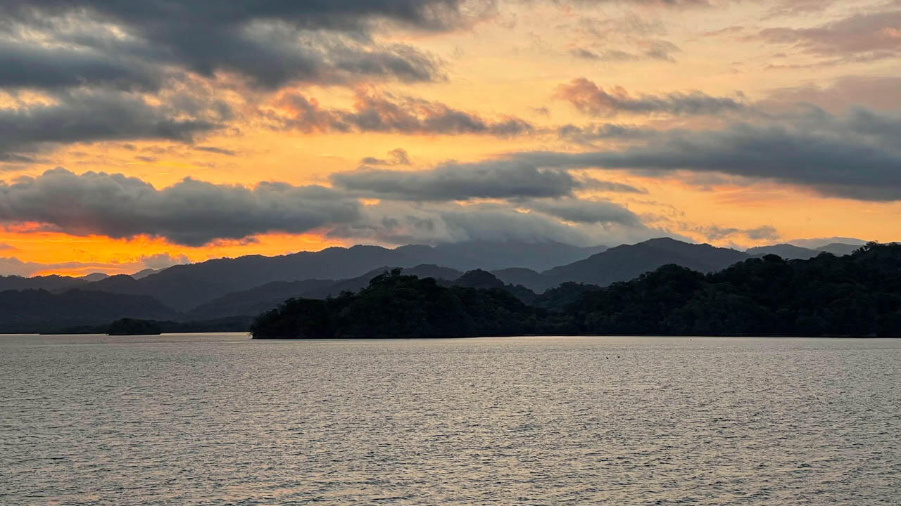 Sunset over the islands on Gulf of Nicoya. White clouds creating foreground on the orange sky.