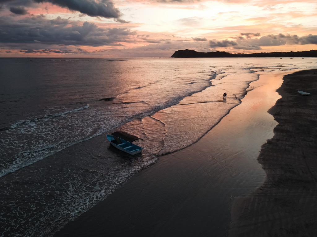 Aerial view of a couple walking on the Samara Beach in Costa Rica at sunset hour.