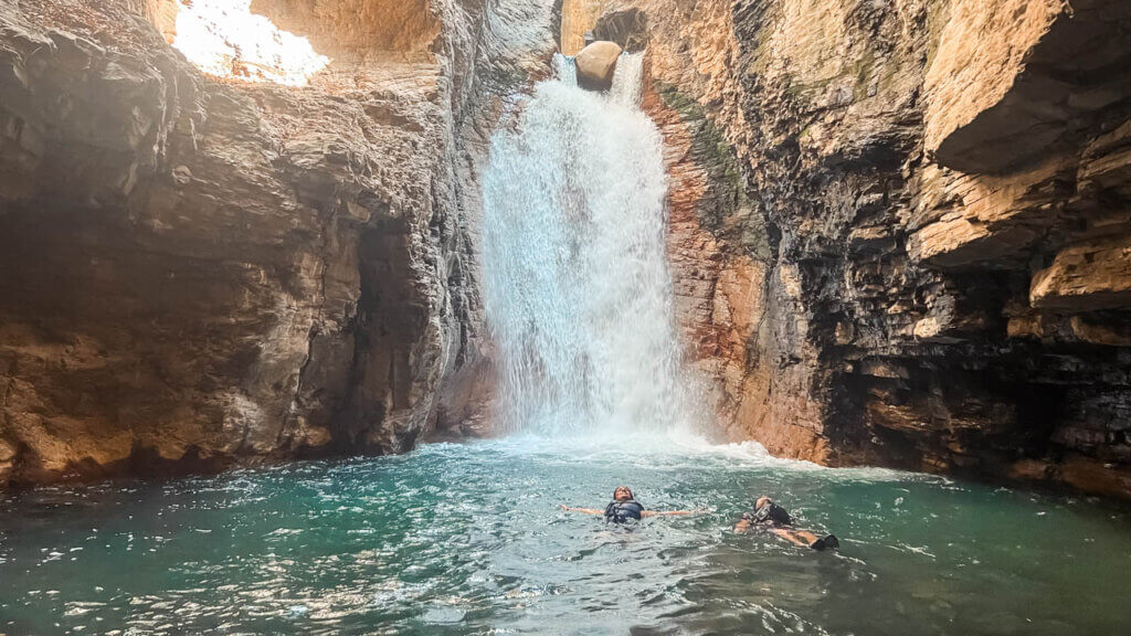 A couple floating at the natural pool of Catarata La Leona.