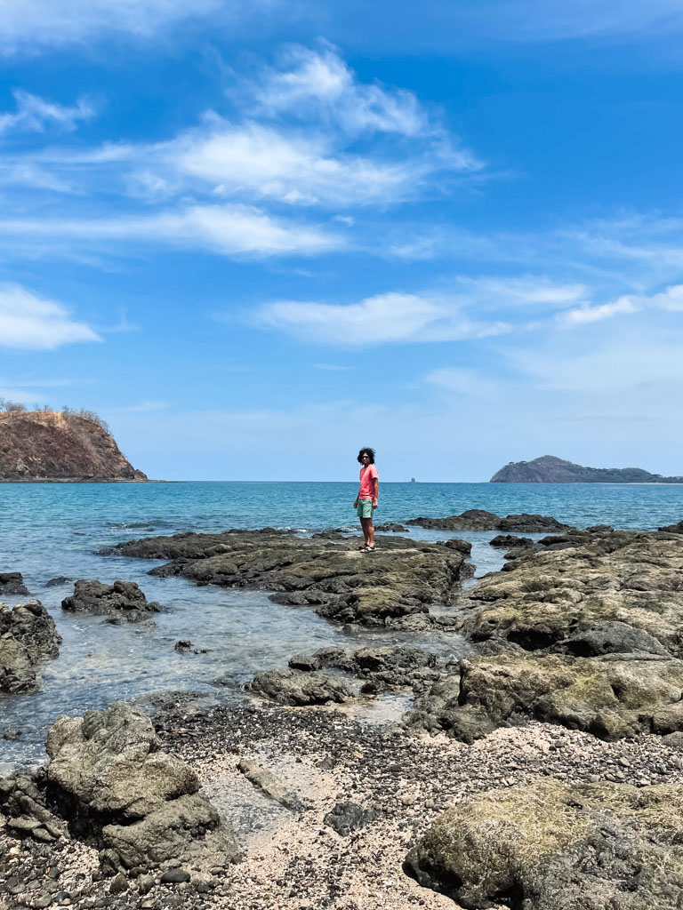 Man, standing on the rocky surface, enjoying the morning sea breeze at Playa Buena, one of the beautiful beaches near Playa del Coco.