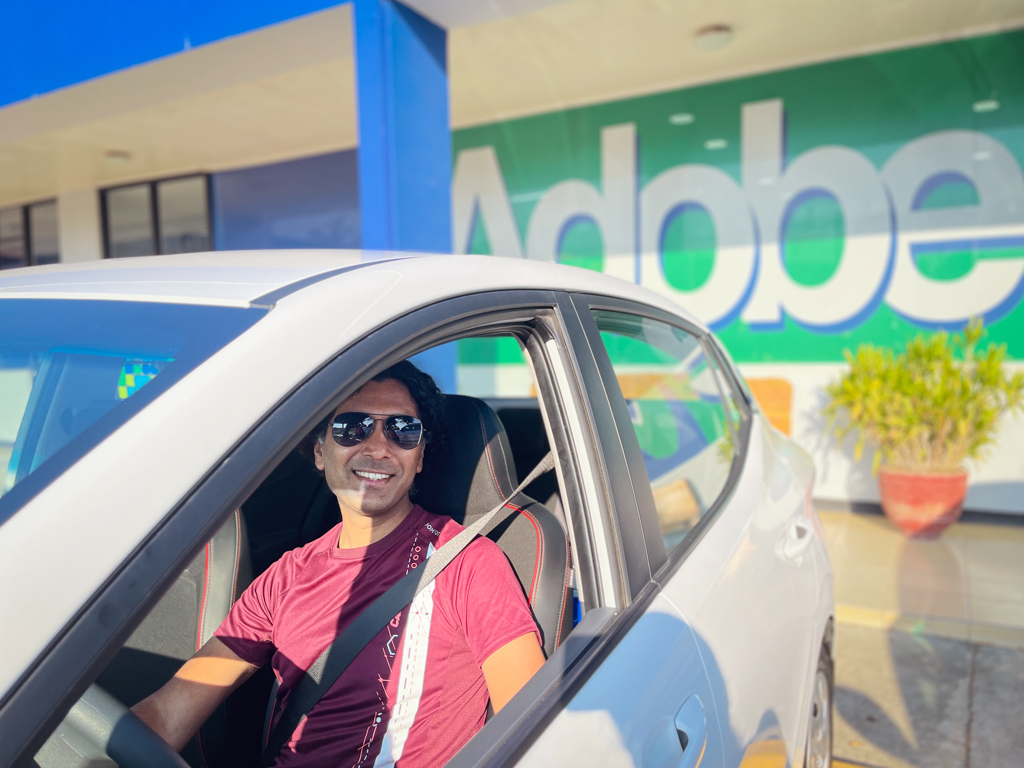 Man, seated at the driver's seat of a rental car at Adobe Rent A Car office in Costa Rica.