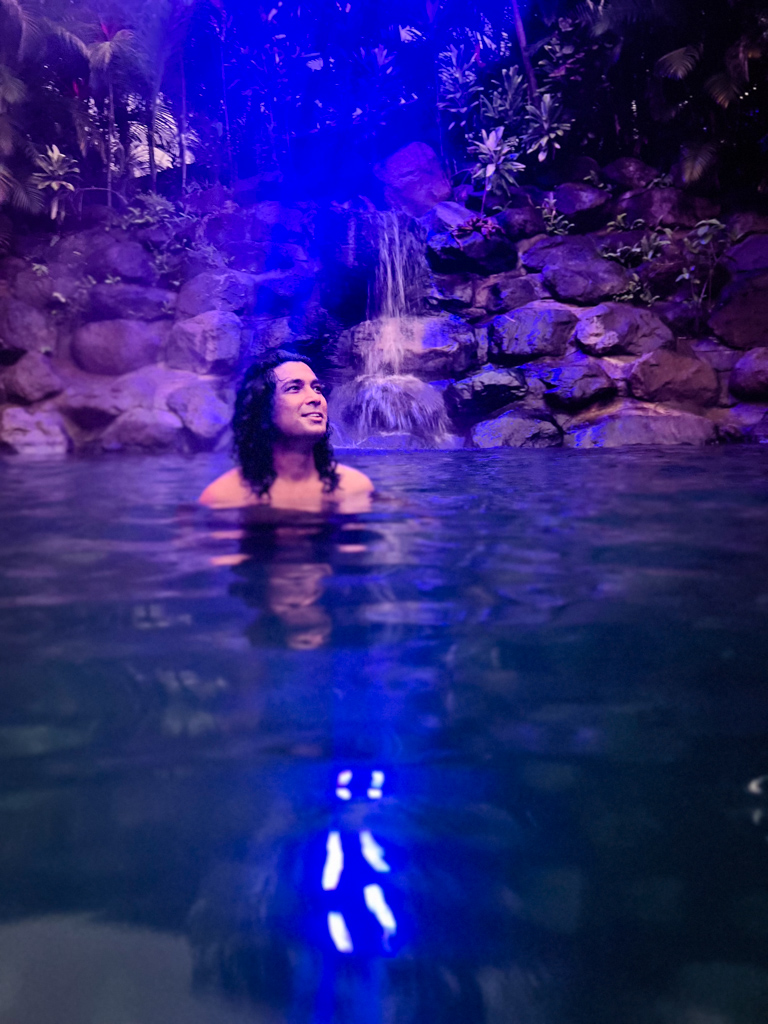 Man, in one of the thermal pools, lit with the night lights.