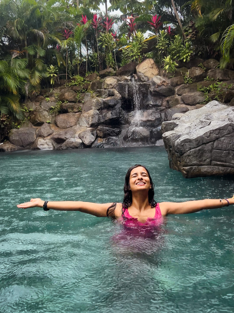 Woman enjoying the rain at a thermal water pool in La Fortuna, Costa Rica.