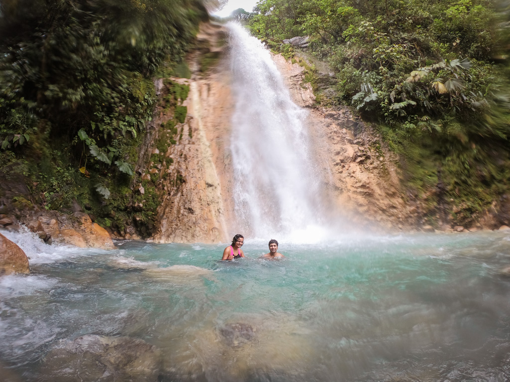 Couple, taking a dip in the pool of Blue Falls on a rainy morning