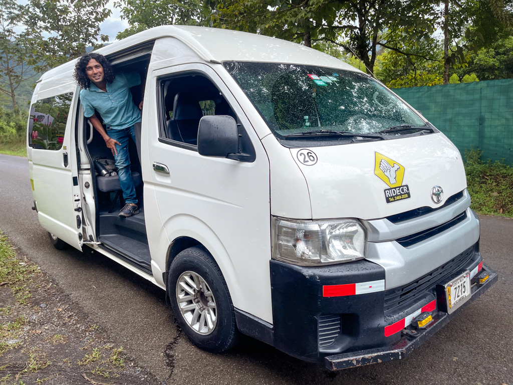 Man, standing at the door of a minivan, a popular and convenient way of transferring from San Jose to La Fortuna and vice-versa.