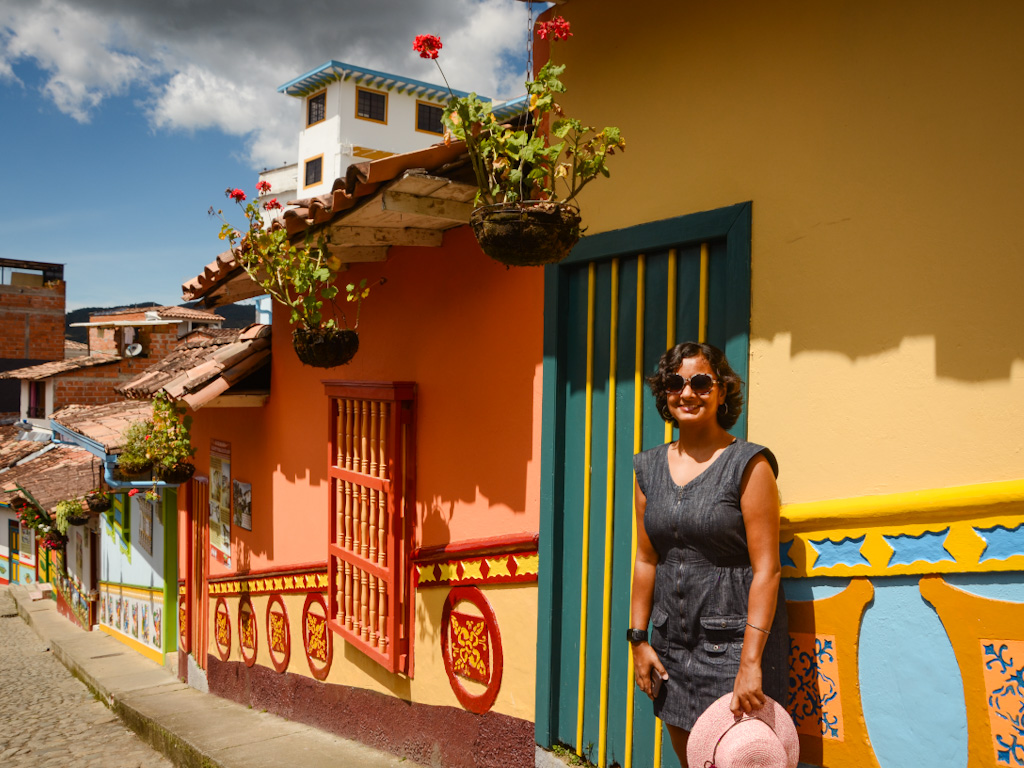 Woman standing against the colorful walls of Guatape town, a nice trip from Medellin.