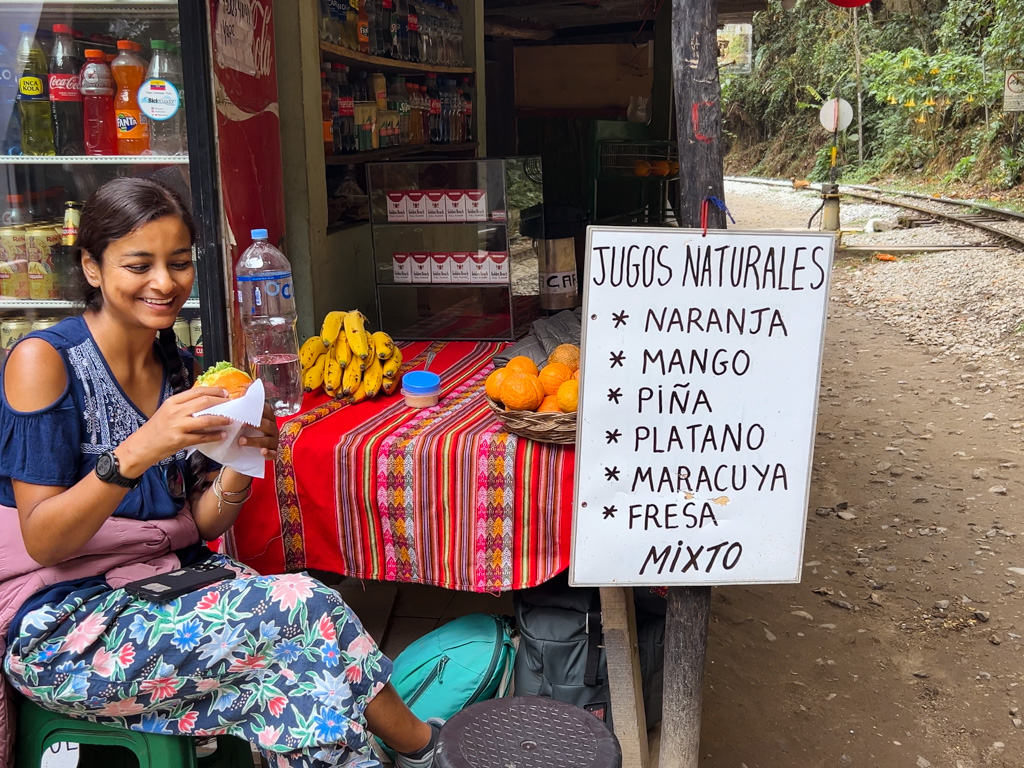 Woman, enjoying a freshly made sandwich at a roadside (railway-track-side) shop, on the way back from Aguas Calientes.