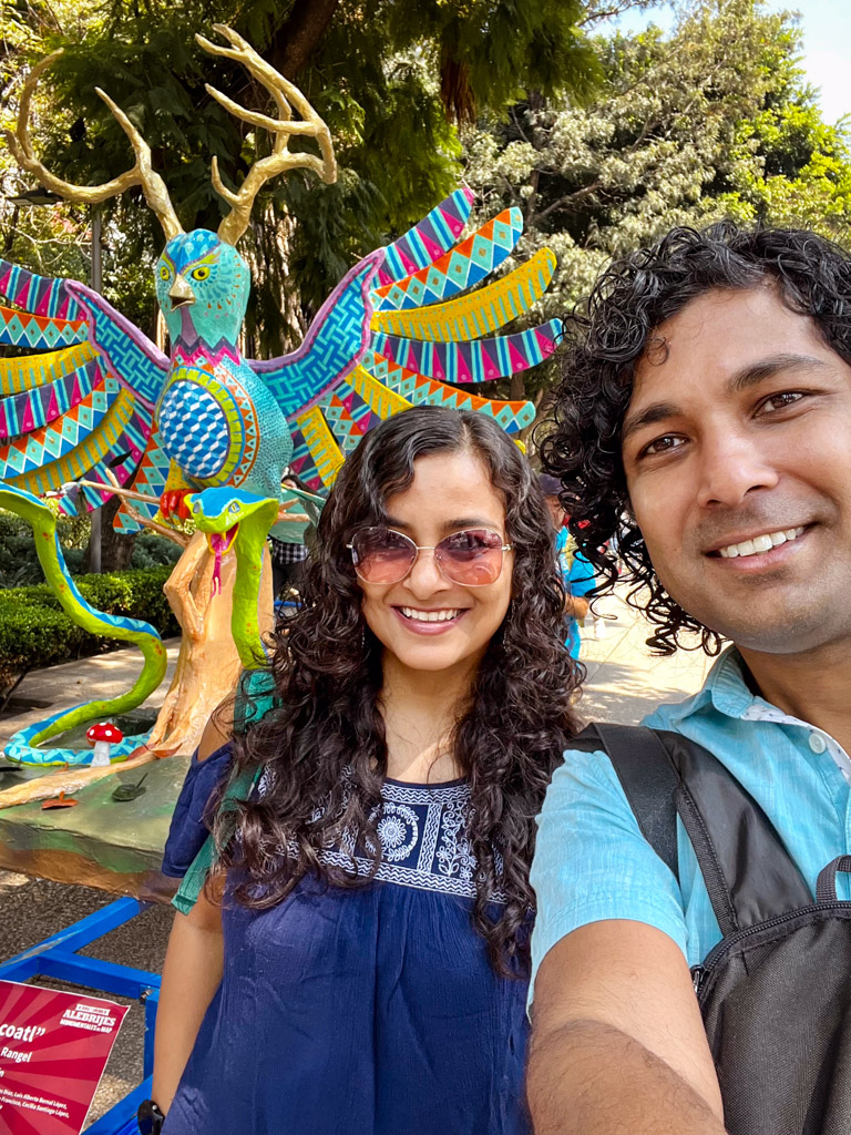 Couple posing for a selfie with an alebrije. Alebrijes Parade is one of the Day of the Dead celebrations in Mexico City.