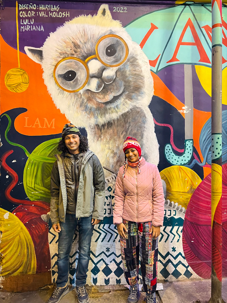 Couple standing against a wall with street art on a cold evening in La Paz, Bolivia.