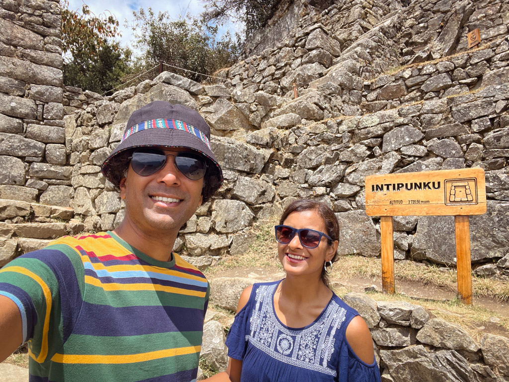 Couple posing for a selfie in front of the sign board with Inti Punku altitude information.