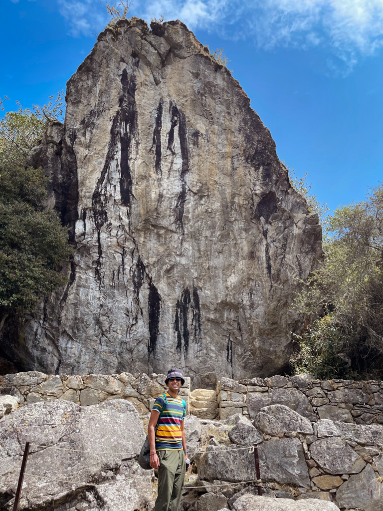 Man standing in front of the giant rock, on the trail to Inti Punku Machu Picchu.